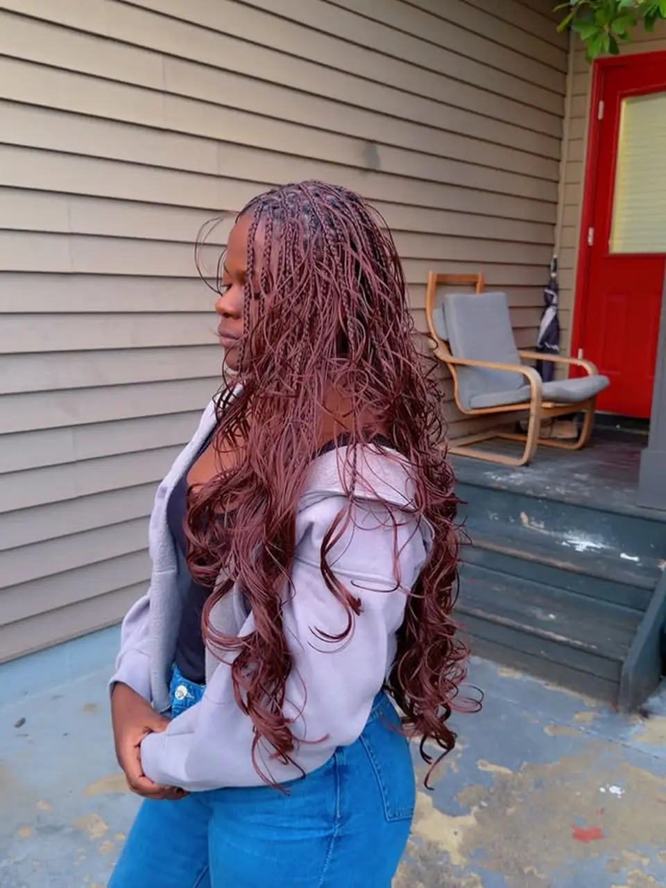 Side view of waist length burgundy boho braids with wavy ends